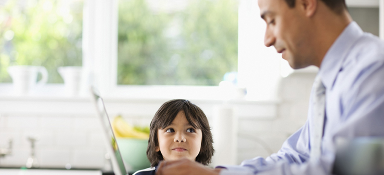 Son watching father use laptop
