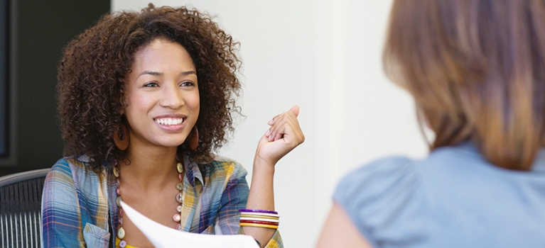 Rear view of a woman giving resume to an African American woman in office