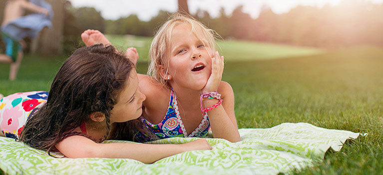 Girls laying in the grass on a blanket